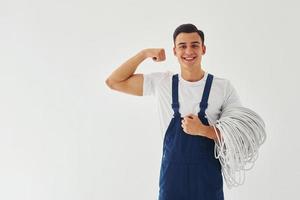 Male worker in blue uniform standing inside of studio against white background photo