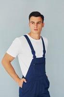 Male worker in blue uniform standing inside of studio against white background photo