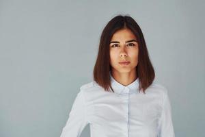 joven mujer moderna con camisa blanca parada dentro del estudio foto