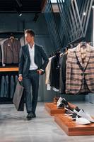 Shopping day. Young guy in modern store with new clothes. Elegant expensive wear for men photo