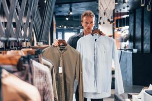 productos de calidad. chico joven en una tienda moderna con ropa nueva. ropa elegante y cara para hombres foto