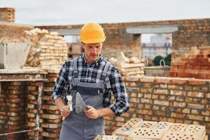 With spatula for construction. Worker in uniform and safety equipment have job on building photo