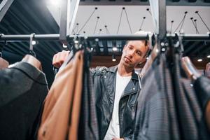 compras de fin de semana. chico joven en una tienda moderna con ropa nueva. ropa elegante y cara para hombres foto