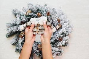 las manos de la mujer sostienen un pequeño suéter. vista superior de la textura festiva de navidad con decoraciones de año nuevo foto