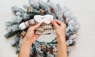 Woman's hands holds little sweater. Top view of christmas festive texture with new year decorations photo