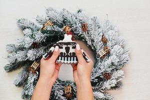 Woman's hands holds little sweater. Top view of christmas festive texture with new year decorations photo