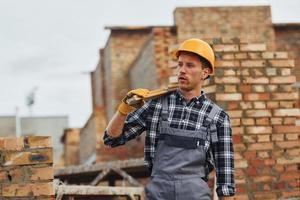 Holds measuring tool and takes break. Construction worker in uniform and safety equipment have job on building photo