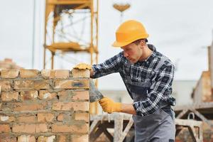 Laying bricks. Construction worker in uniform and safety equipment have job on building photo