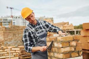 With spatula for construction. Worker in uniform and safety equipment have job on building photo