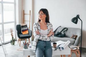 Standing near table. Young female freelance worker is indoors in home at daytime photo