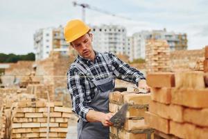 With spatula for construction. Worker in uniform and safety equipment have job on building photo