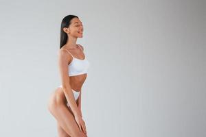 In white underwear. Woman with sportive slim body type that is in the studio photo