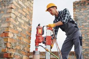 Uses blending drill. Construction worker in uniform and safety equipment have job on building photo