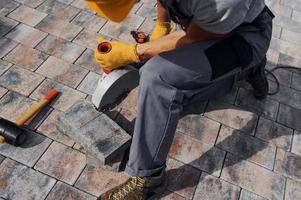 Close up view. Male worker in yellow colored uniform have job with pavement photo
