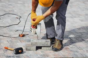 Concentrated at work. Man in yellow colored uniform have job with pavement photo