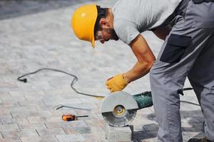 Concentrated at work. Man in yellow colored uniform have job with pavement photo