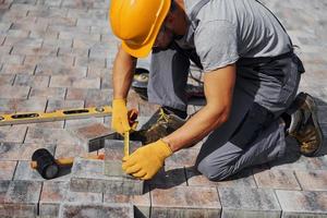 Measuring process. Male worker in yellow colored uniform have job with pavement photo