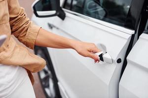 abre la puerta. mujer joven hermosa de moda y su automóvil moderno foto