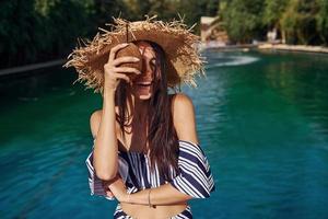 In straw hat. Girl have fun and rest in swimming pool at daytime. Conception of vacation photo