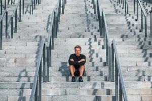 Young man in sportive clothes have workout outdoors at daytime photo