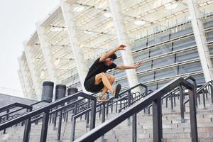 Doing parkour. Young man in sportive clothes have workout outdoors at daytime photo