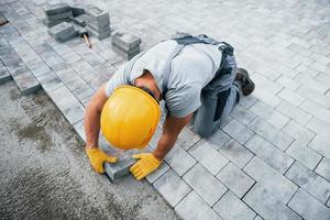 Concentrated at work. Man in yellow colored uniform have job with pavement photo