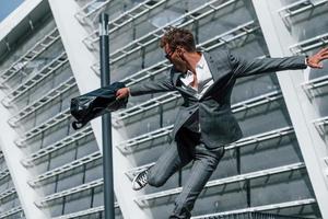 Celebrating success. Young businessman in grey formal wear is outdoors in the city photo