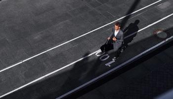 Young successful businessman in grey formal wear is outdoors in the city photo