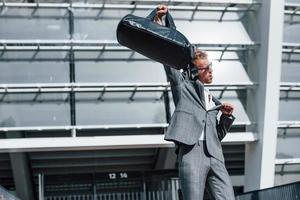 Celebrating success. Young businessman in grey formal wear is outdoors in the city photo