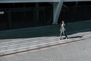 muestra el dedo medio. joven empresario exitoso en ropa formal gris está al aire libre en la ciudad foto