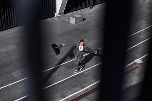 celebrando el éxito. un joven hombre de negocios con ropa formal gris está al aire libre en la ciudad foto