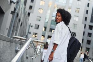 African american woman in good clothes is outdoors in the city at daytime photo