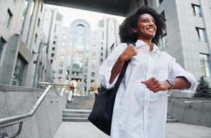 African american woman in good clothes is outdoors in the city at daytime photo