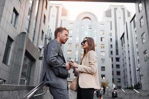 Girl holds drink. Woman and man in the town at daytime. Well dressed people photo