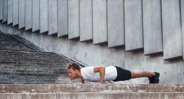 Against building exterior. Young man in sportive clothes have workout outdoors at daytime photo