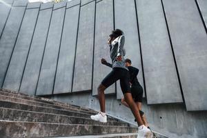 Near big wall. European man and african american woman in sportive clothes have workout together photo