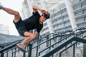 correr y saltar. un joven con ropa deportiva hace ejercicio al aire libre durante el día foto