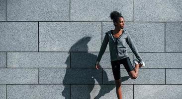 Young african american woman in sportive clothes have workout outdoors at daytime photo