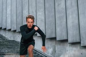 Runs forward. Young man in sportive clothes have workout outdoors at daytime photo