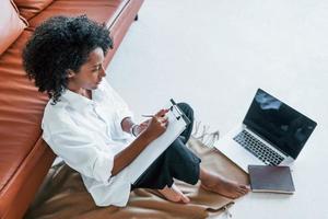With laptop. Young african american woman with curly hair indoors at home photo