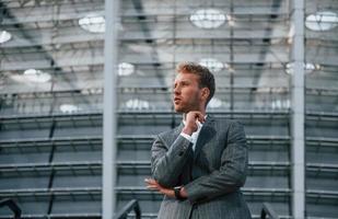 On the stairs of stadium. Young businessman in grey formal wear is outdoors in the city photo