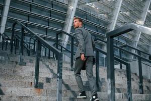 un joven hombre de negocios con ropa formal gris está al aire libre en la ciudad foto