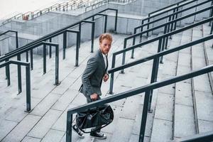 Urban beauty. Young businessman in grey formal wear is outdoors in the city photo