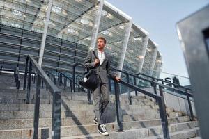 Young businessman in grey formal wear is outdoors in the city photo