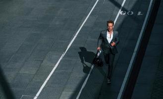 View from the top. Young businessman in grey formal wear is outdoors in the city photo