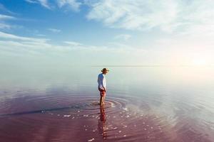 Guy in casual clothes have a walk in the pink and purple colored shallow water photo