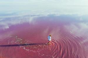 Guy in casual clothes have a walk in the pink and purple colored shallow water photo