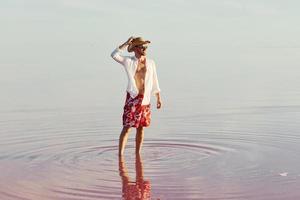 Man in hat and casual clothes walks on lake at Jarilgach island, Ukraine photo