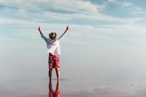 Enjoying majestic view. Man in hat and casual clothes walks on lake at Jarilgach island, Ukraine photo