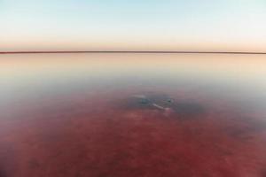 Distant view of lake in the Jarilgach island in Ukraine at daytime. Red colored water photo